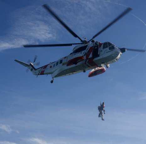 Operación de auxilio en la ría de Ares. Arriba, a la izquierda, un rescatador se descuelga para nadar hasta el «Oreus». Allí (derecha) espera por su compañero, que hará de víctima. Una vez en el barco, el rescatador lo engancha a su arnés y ambos, desde el agua (abajo a la izquierda) son izados al «Helimer 210» (foto central). FOTOS JUAN OLIVER